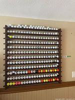 Full front view of dark-stained wooden rack filled with golf balls on 12 rows