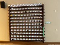Full front view of dark-stained wooden rack loaded with rows of white golf balls displaying assorted logos