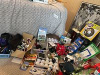Photo of assorted golfing items including golf balls, tees, novelty golf toys, and various small accessories spread on floor near a bed.
