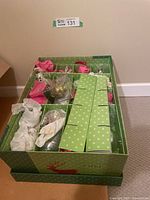 Green storage box holding Christmas ornaments, some wrapped and compartmentalized