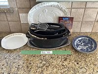 Overview of all items including 3 roasters with lids, serving platters, skewers, and a box of oven bags arranged on countertop.