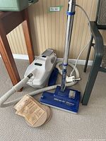 Full view of Miracle Mate vacuum cleaner with power head, floor head, hose and extra vacuum bags laid out on carpeted floor.