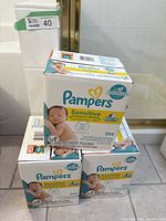 Three unopened boxes of Pampers Sensitive baby wipes stacked, each box containing 504 wipes for sensitive skin.