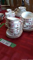 Overview of stacked soup bowls and underplates on red tablecloth