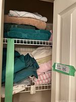 View of stacked towels and folded table linens inside a closet showing a range of colors and textures
