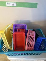 Photo showing multiple colorful plastic baskets in varying rectangular and rounded shapes with various ventilation holes and lattice designs, set inside a large blue plastic basket