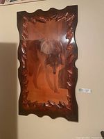 Full view of vintage wolf picture with dark carved wood frame on wall.