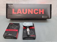 Box labeled LAUNCH in large red letters and two sensor packs with one sensor with protective rubber cap on valve