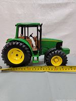 Side view of John Deere 6320 tractor model with measuring tape showing approx 7 inch length