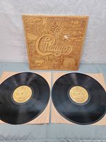 Photo showing embossed cover sleeve with Chicago logo and farming artwork in a tan color, with two vinyl records below on sleeves.