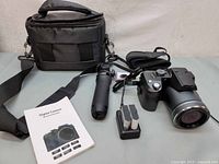 Photo showing full lot including camera, charger with batteries, tripod grip, hand straps, and carrying case.