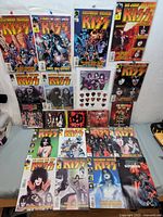 Full layout of the KISS comics, DVD, and guitar picks showing all items in the lot.