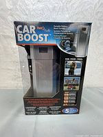 Photo of the boxed Car Boost Portable Battery Boost System showing device inside packaging and usage for cars, motorcycles, and boats.
