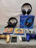 PlayStation accessories including wireless headset with box, two PS4 controllers, three PS4 games, two Game Boy cartridges, and Nintendo Wi-Fi USB connector.