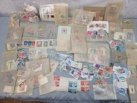 Wide view of all stamps spread on surface including many loose stamps and envelopes