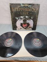 Two black vinyl records with Dunhill labels laid flat in front of the album cover.