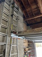 Overall view of ladder hanging against brick wall in partially extended configuration