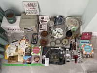 Photo showing full scope of lot including metal ice bucket, glassware, coasters, corkscrews, bottle openers, paper labels, and cocktail books.
