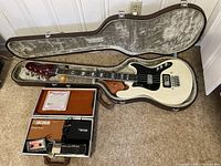 Bass guitar and hard case open on floor with accessories arranged