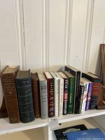 Shelf of various hardcover books including The New Webster Dictionary, Gray's Anatomy, Bob Woodward Fear, James Bond, and others.