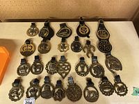 Overview of all brass horse brasses laid out in rows on table