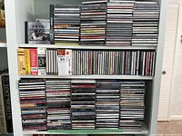 Four shelves filled with stacks and rows of jewel-case CDs