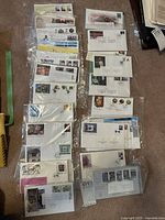 Overview of multiple envelopes in plastic sleeves showing various first day issuance stamps with diverse themes and postmarks.