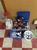 Large collection of golf balls in multiple containers like buckets, bins and boxes with various brands and some related golf items.