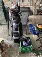 Full view of Nike golf bag with clubs standing next to milk crate holding golf balls and bag of gloves