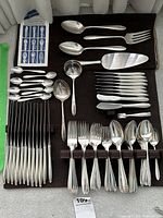 Top-down view of entire flatware assortment on felt pad with pamphlet visible