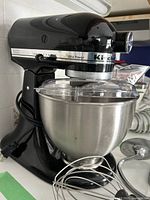 Side view of black tilt-head mixer mounted with bowl and whisk