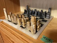 Full view of the chess board with all beige and black marble pieces set up, showing alternating marble squares and carved pieces.