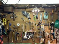 Wide view of pegboard showing multiple vintage hand tools including drills, levels, mallets, saws, and pliers.