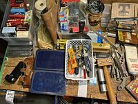 Overview of the workbench surface showing various hand tools including screwdrivers, a hand saw, hammer, C-clamp, vice grips, and a small caddy with assorted hardware.