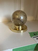 Baseball inside clear acrylic case on brass stand viewed front