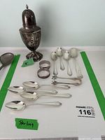 Overview of sterling silver sugar shaker, ladle, spoons, tongs, and napkin rings