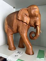 Side profile of the carved wooden elephant showing detailed texture on body and legs.
