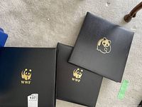 Three black WWF binders with gold panda logo on covers, placed on carpet.