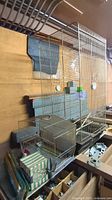 Large bird cage with attached bird feeders and some bird supplies around it