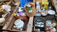 Photo showing assorted electrical and lighting items including lamps, fixtures, bulbs and switches packed in boxes and on wooden pallets.