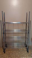 Front view of metal shelving unit with wire shelves and caster wheels
