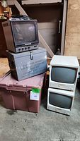 Three vintage monitors: one Yutek monitor with multiple control knobs and two stacked smaller Shisaden monitors, placed on plastic bins.