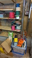 Photo of shelves with multiple large spools of colored wire including red, green, and beige on wooden shelves above plastic bins