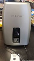 Front view of the silver Air-O-Swiss humidifier with power cord visible and brand name printed on the front.