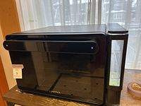 Front view of black Anova steam oven with glass door and water reservoir