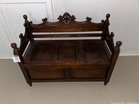 Front view of antique wooden bench chest showing carved backrest and finials