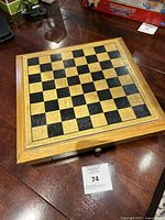 Top-down photo of wooden chessboard showing black and natural wood squares in a framed square board.