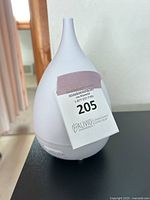 White teardrop shaped ceramic or plastic essential oil diffuser with control buttons on the base. Missing plug is confirmed from seller description.