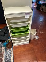 Front view of IKEA Trofast storage unit showing six sliding plastic bins (white and green) inside a white frame.