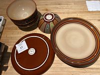 Seven-piece set of Sango ceramic plates and bowls arranged on wooden surface, showing top and bottom views.